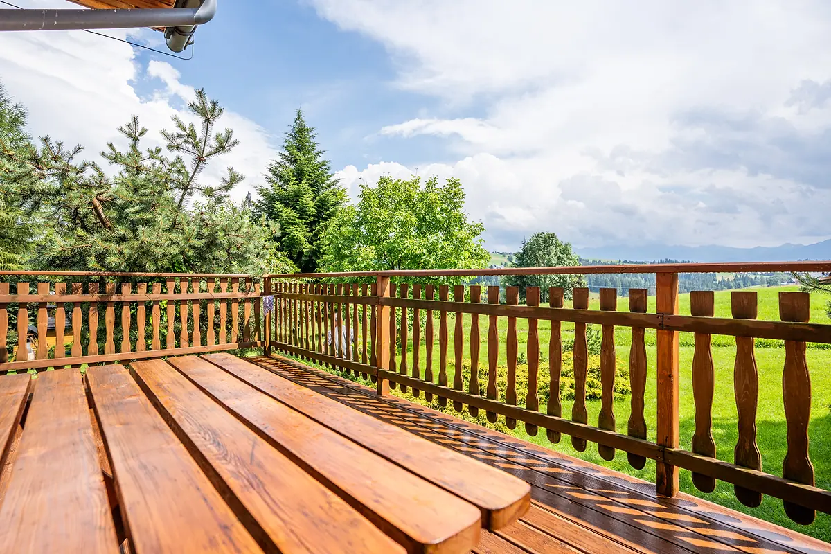 Balkon z drewnianą ławą i widokiem na łąki