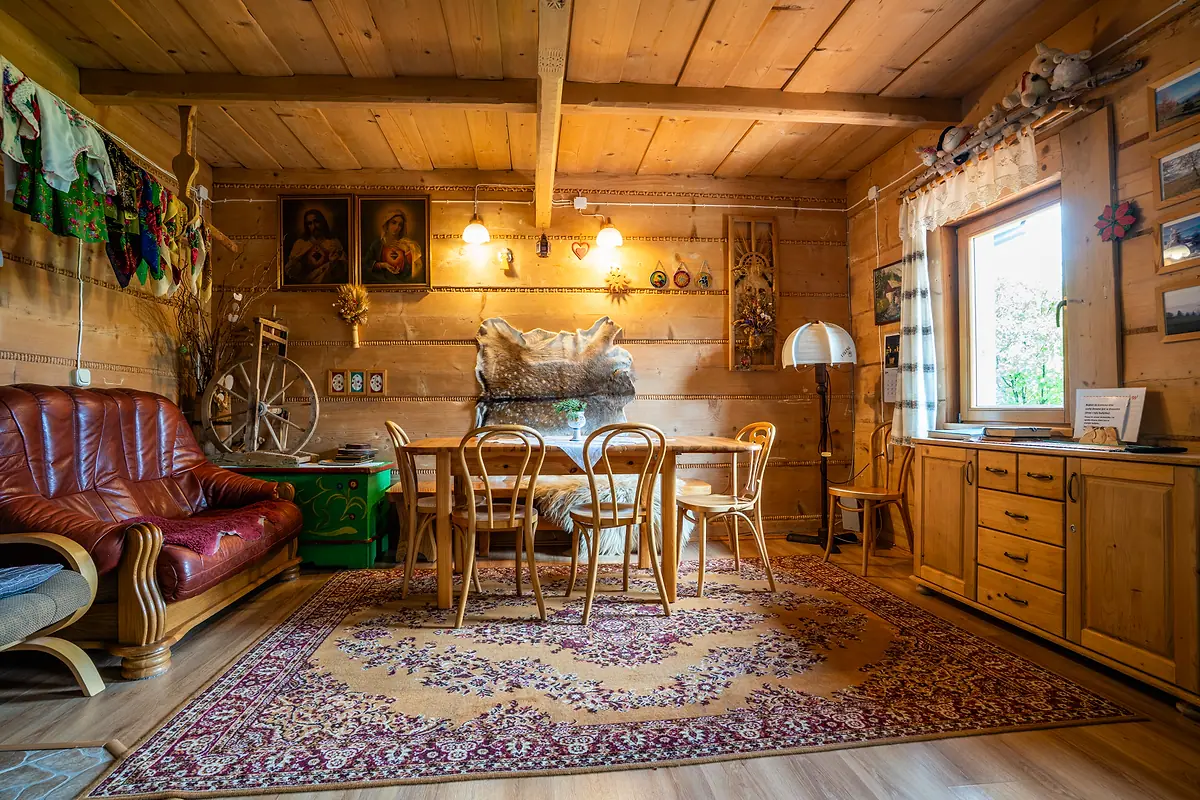 Salon w góralskim stylu — kołowrotek, obrazy i drewniane ściany